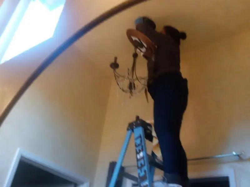 Electrician installing a chandelier in a Tucumcari residence